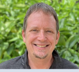 Headshot of man smiling outdoors.