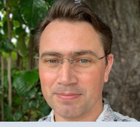 Headshot of man smiling in outdoors.